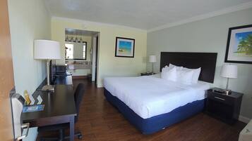 A hotel room with a bed, desk, chair, and a bathroom visible in the background.