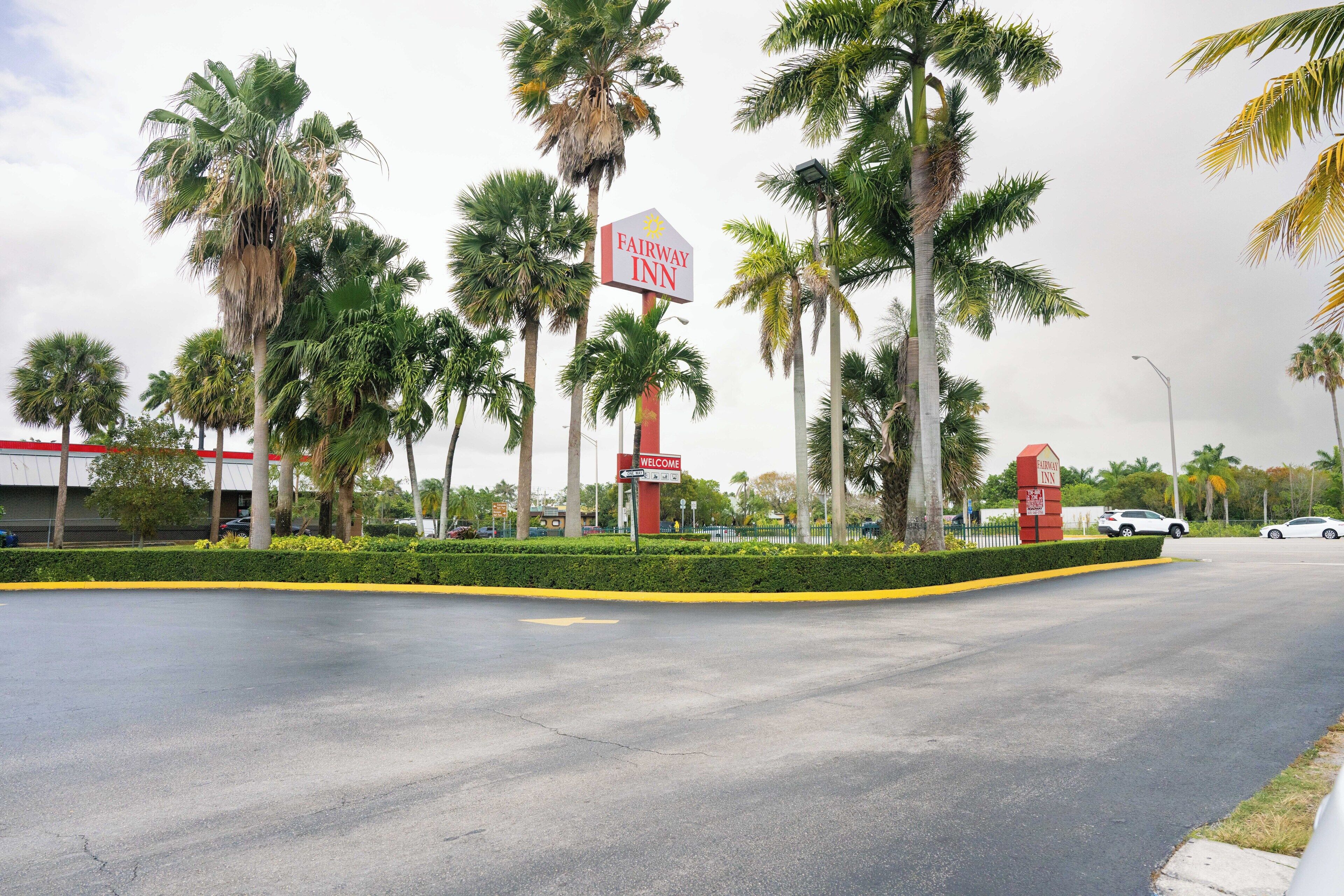 A Fairway Inn sign with palm trees and a parking lot.