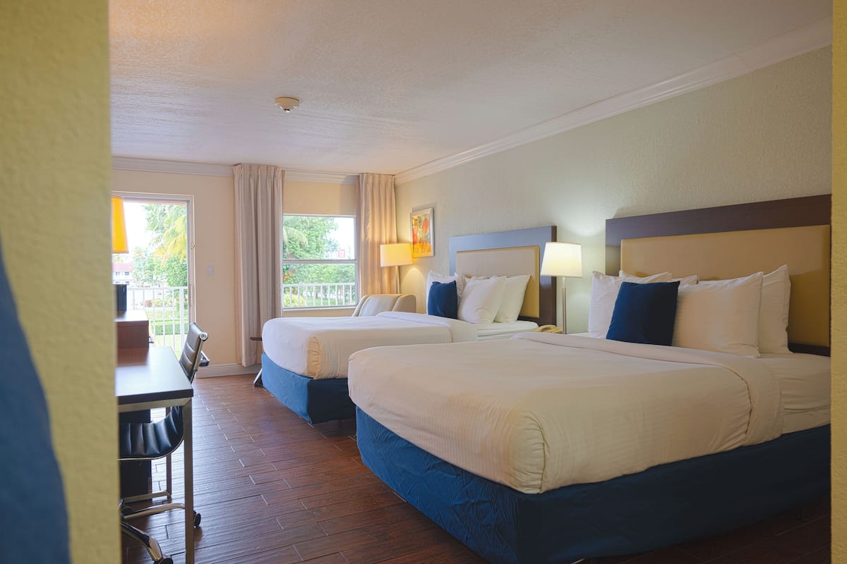 Une chambre d’hôtel avec deux lits, un bureau et une fenêtre avec des rideaux.
