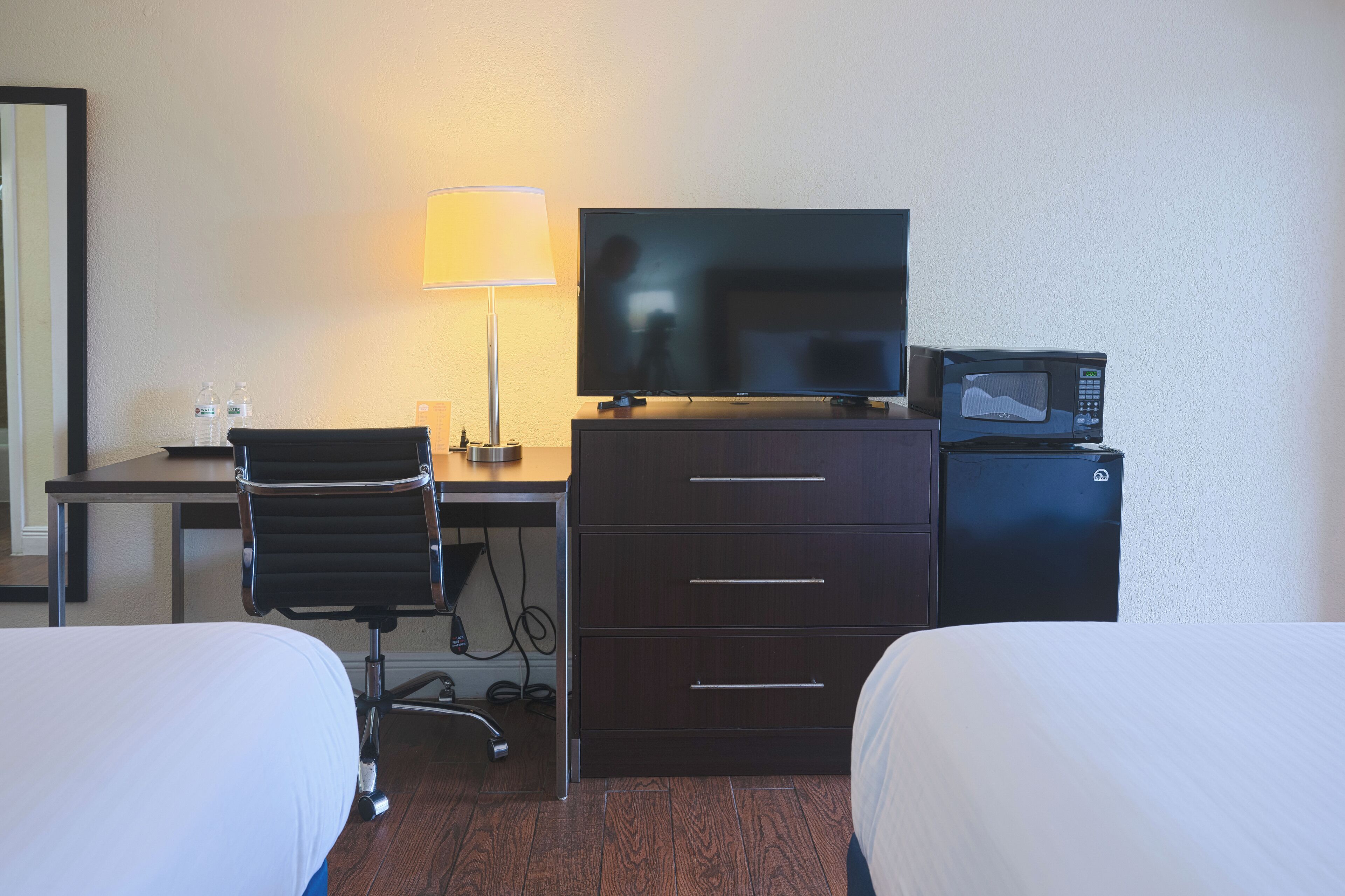 Une chambre d’hôtel équipée d’un lit, d’un bureau avec une lampe, d’une télévision et d’un four à micro-ondes.
