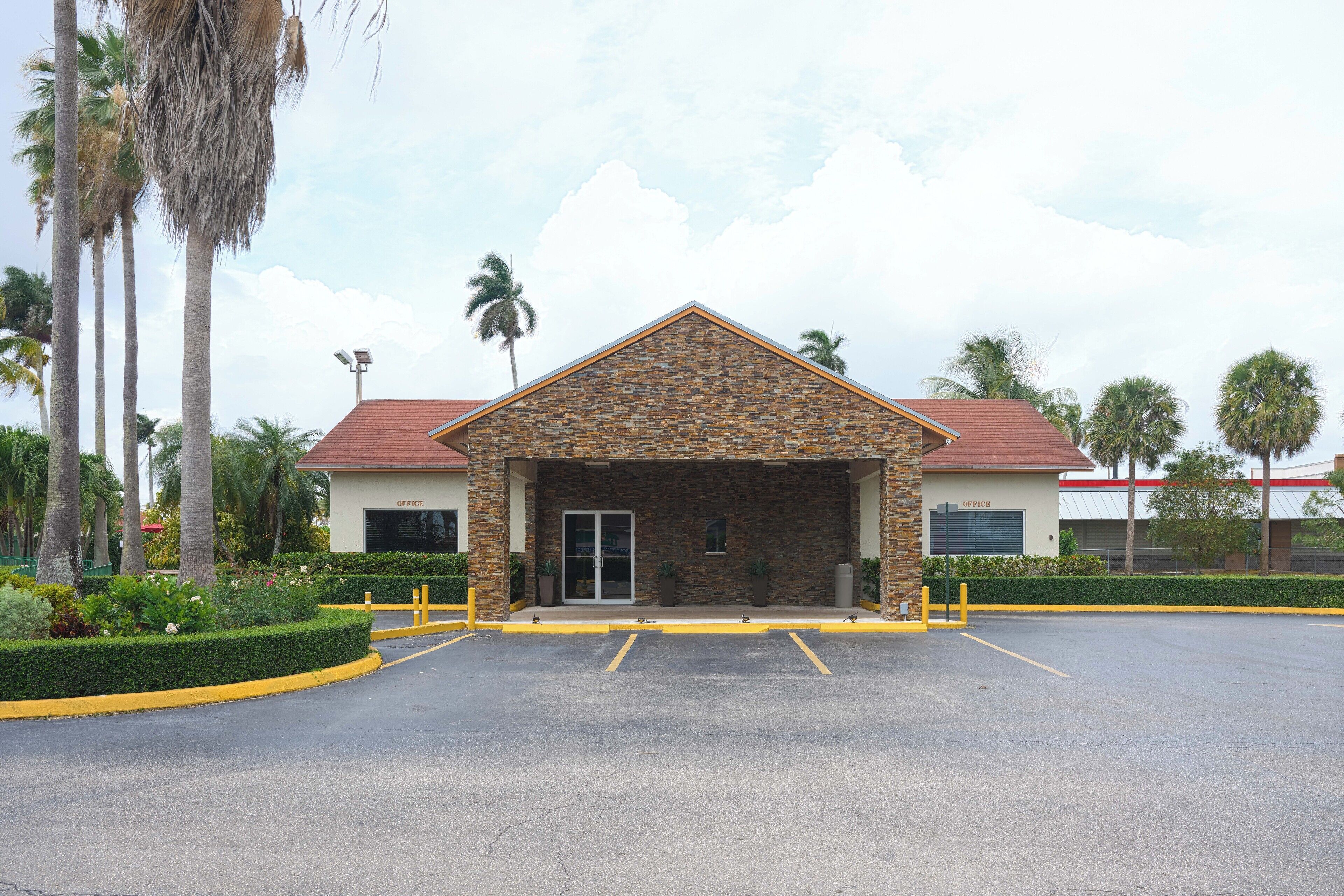 A building with a stone facade, a red roof, and a parking lot with yellow lines.