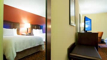 A hotel room with a bed, bedside table, lamp, and a television on a stand.