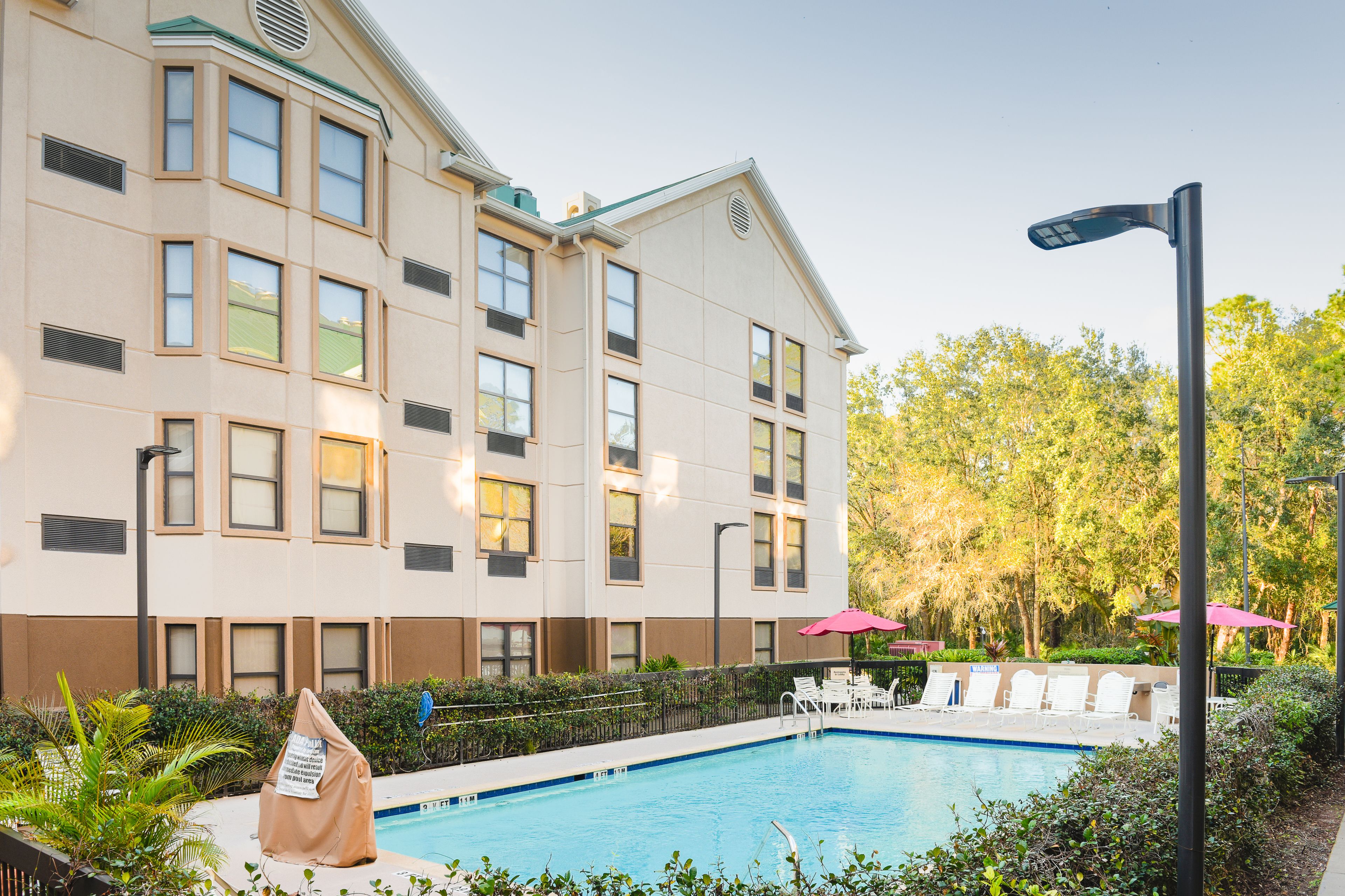 Un hotel con piscina, zona de estar al aire libre y un jardín bien cuidado.