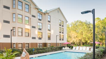 Un hotel con piscina, zona de estar al aire libre y un jardín bien cuidado.