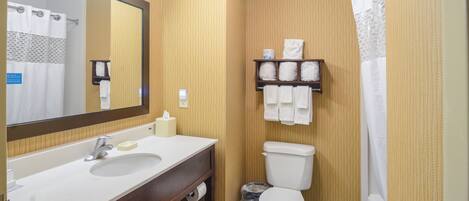 A bathroom with a sink, mirror, toilet, and shower curtain.