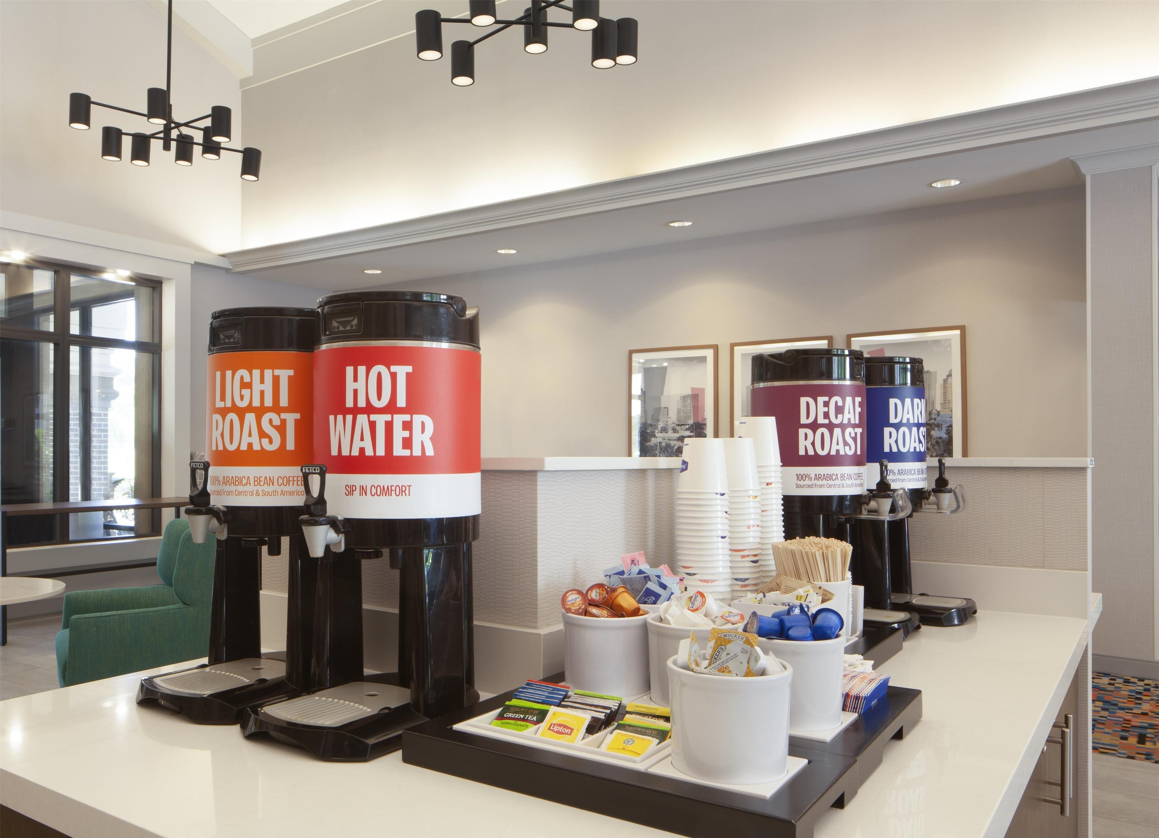 A coffee station with multiple coffee dispensers labeled "Light Roast" and "Hot Water," and a "Decaf Roast" dispenser.