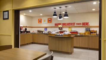 Un área de desayuno con armarios de madera, una isla central con alimentos y un letrero que dice "HAPPY BREAKFAST STARTS HERE".