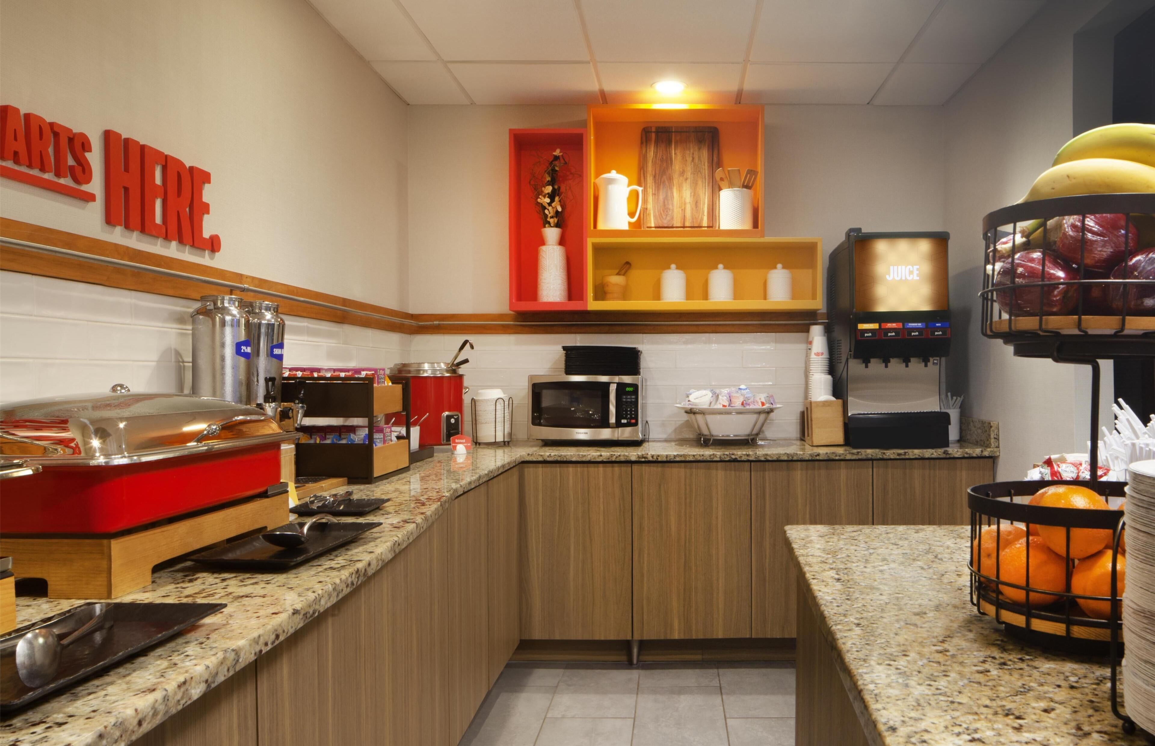 Un buffet proposant une variété de plats et un coin où l’on peut se servir des jus de fruits.