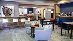 Eine moderne Hotelhalle mit Empfangsbereich, Sitzgelegenheiten mit Sesseln und Sofas, einem Esstisch mit Stühlen und einer Bar mit Theke und verschiedenen Gegenständen.