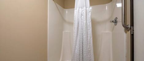 A shower with a white curtain, a grab bar, and a handheld showerhead.