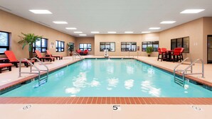 A swimming pool with red chairs and a lifeguard chair, surrounded by windows and potted plants. - Hampton Inn Columbus/Taylorsville/Edinburgh (Edinburgh)