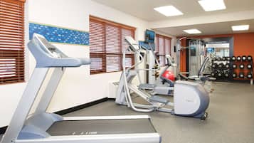 Un gimnasio con cintas de correr, elípticas y equipamiento de levantamiento de pesas.
