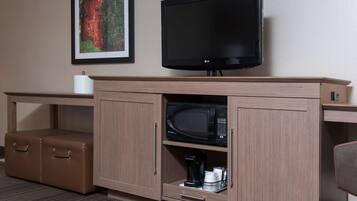 Un mueble de madera con un televisor de pantalla plana, un microondas y una cafetera.