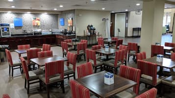 Un restaurante con cabinas y mesas, una barra con menú, y una pared de azulejos con anuncios.