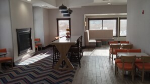 Ein moderner Essbereich mit einem zentralen Holztisch, orangefarbenen Stühlen und einem gemusterten Teppich.