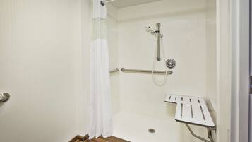 A shower area with a grab bar, a showerhead, and a shower seat.