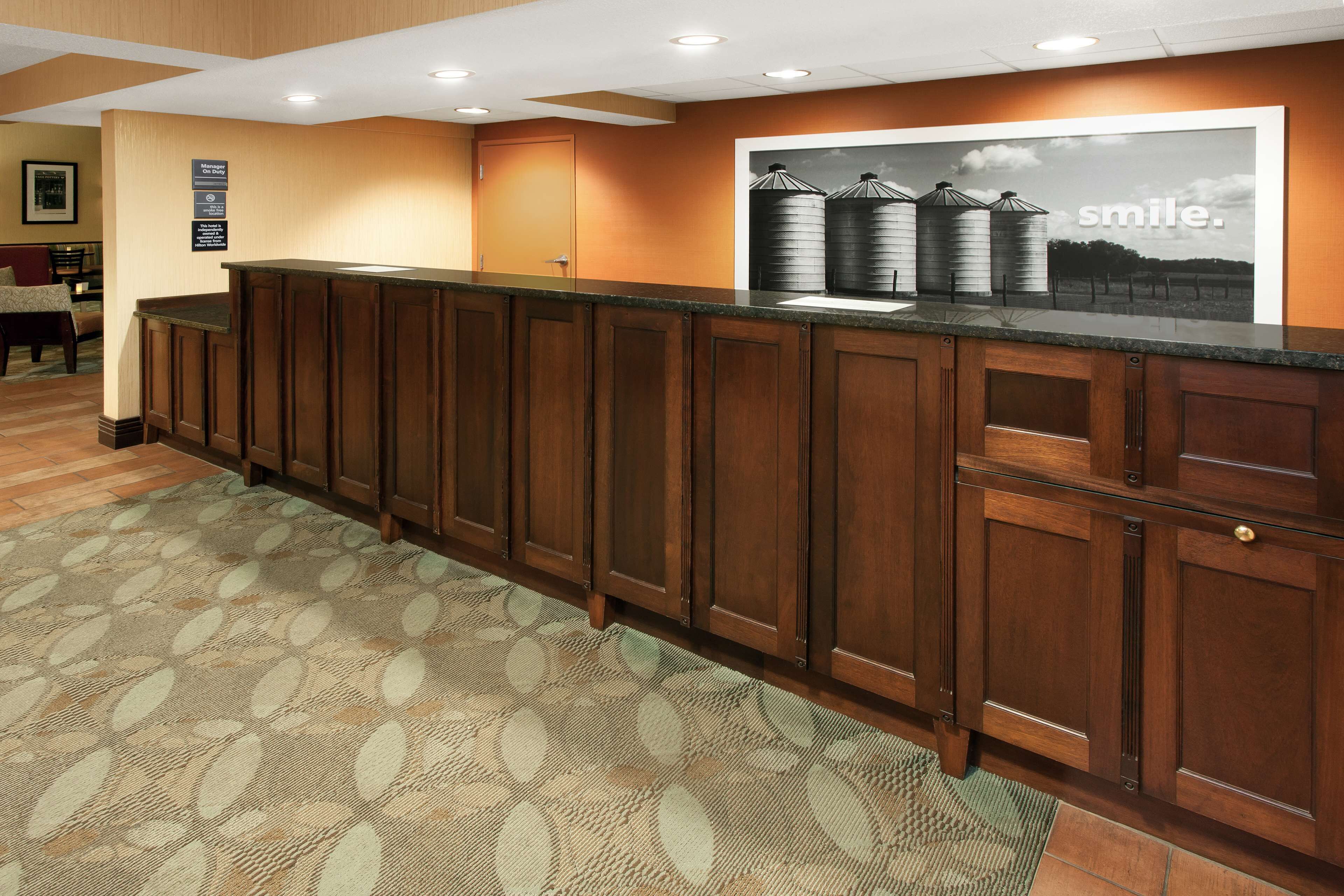 A reception area with a wooden counter, a patterned carpet, and a framed picture on the wall.