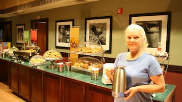 A buffet counter with various food items and a coffee pot.