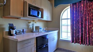 A compact kitchen with a microwave, coffee maker, and a sink. - Key West Inn Tunica (Robinsonville)