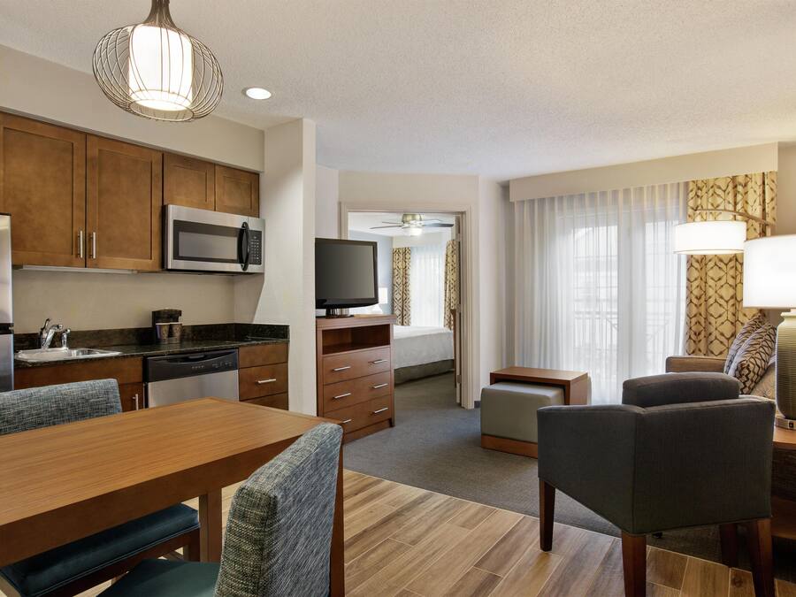 Una habitación de hotel compacta con kitchenette, zona de comedor, sala de estar y televisor.