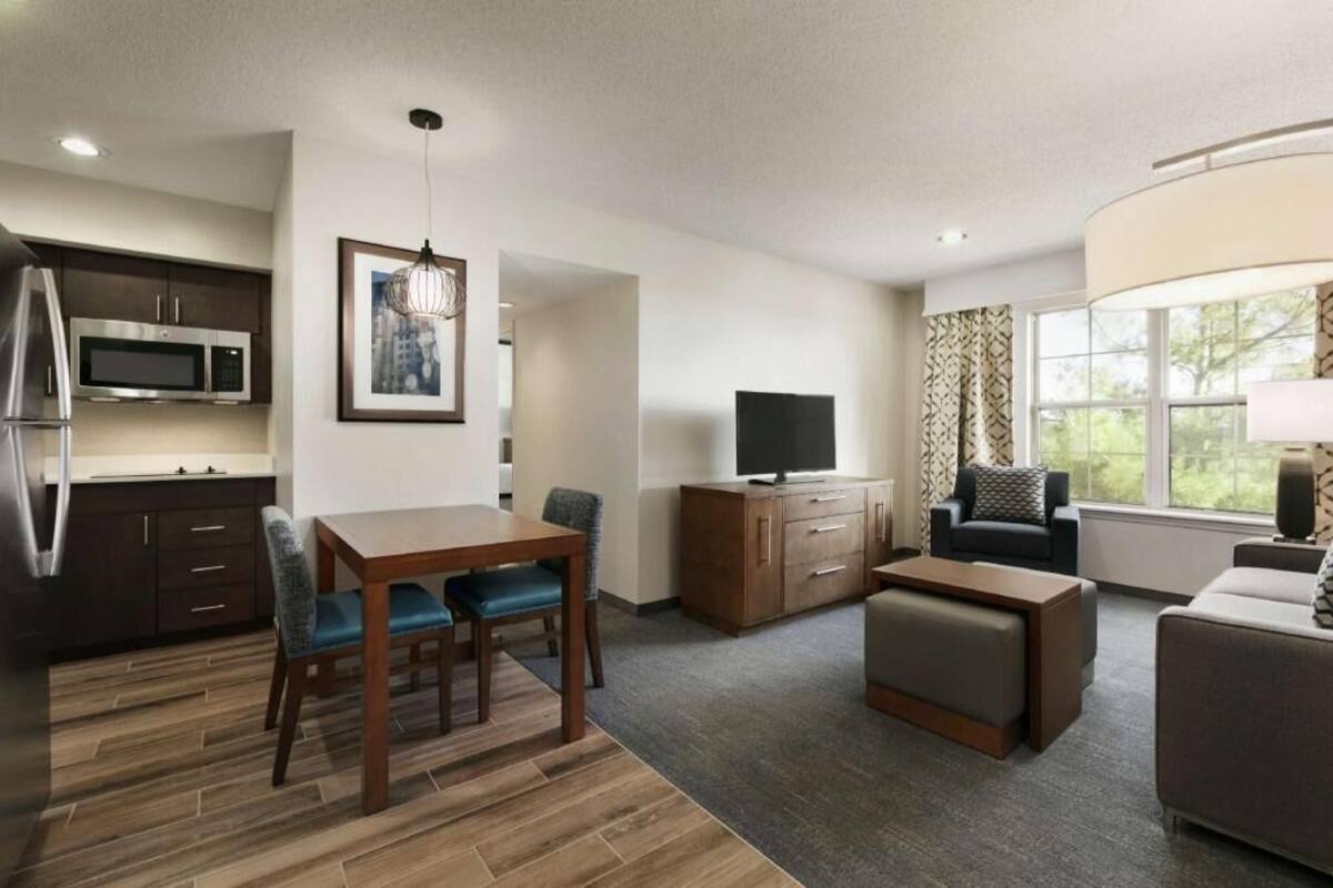A modern living room with a dining area, a flat-screen TV, and a sofa.