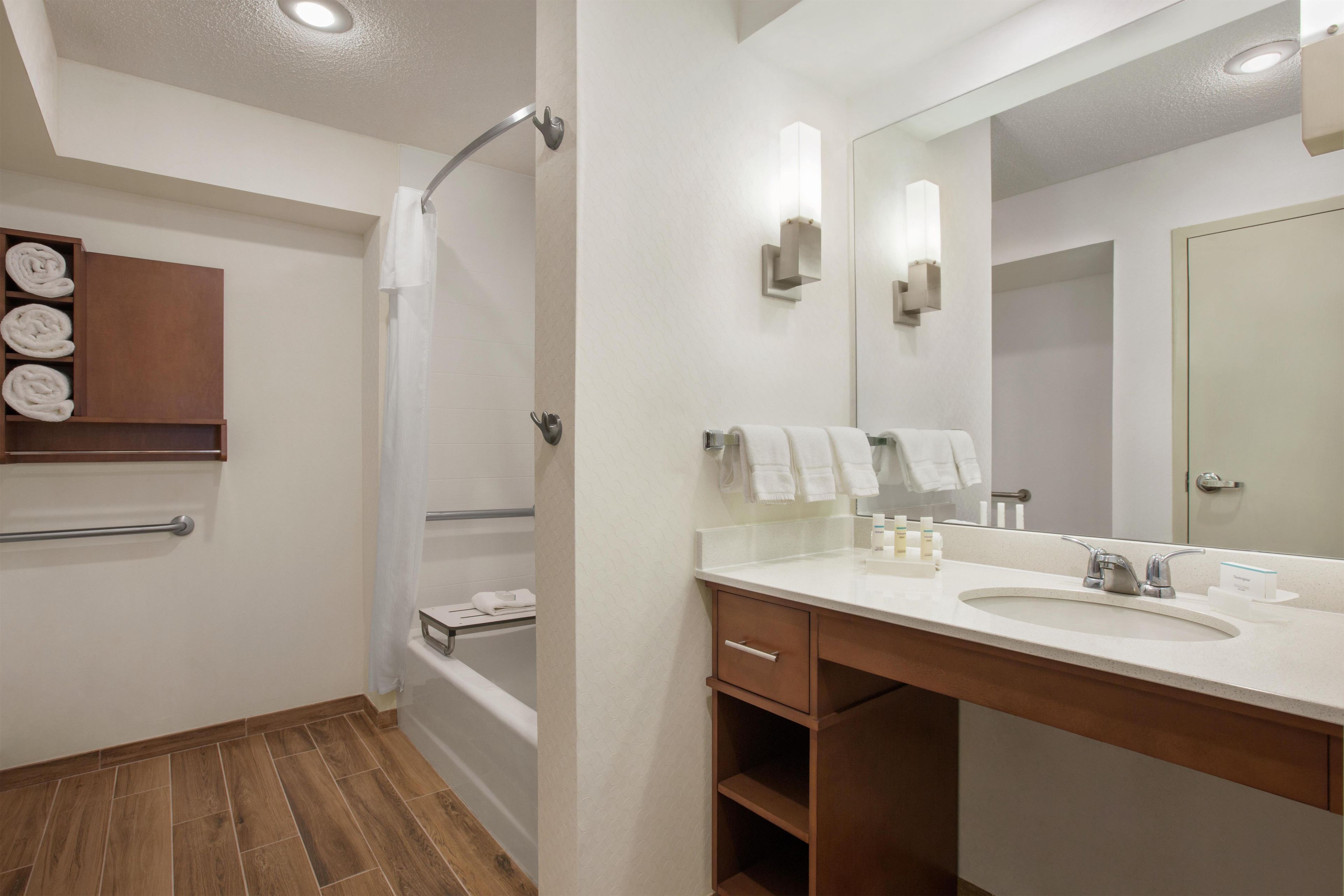 A modern bathroom with a shower, a vanity with a sink, and a large mirror.