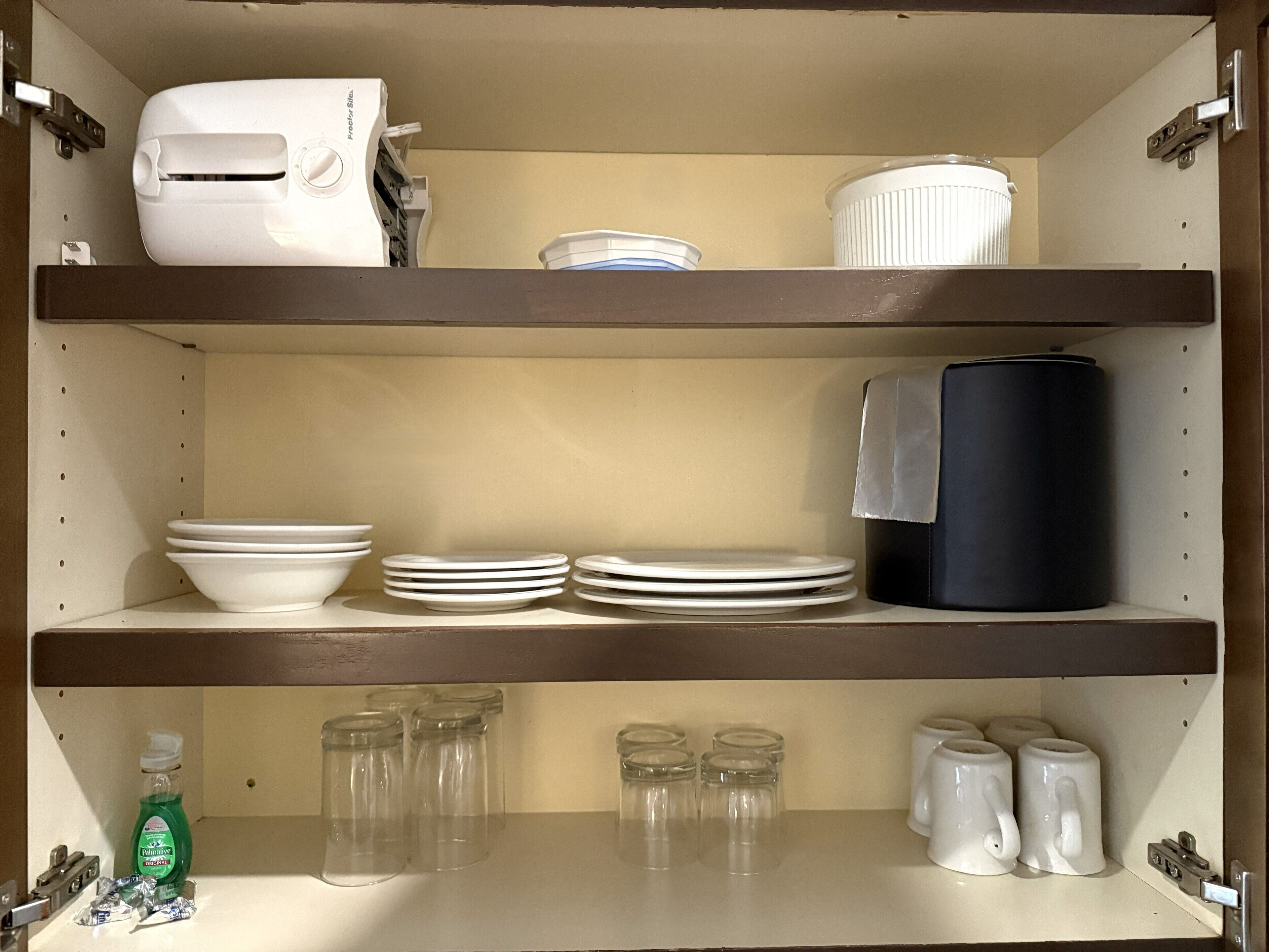 A kitchen with three shelves, each holding various kitchenware and appliances.