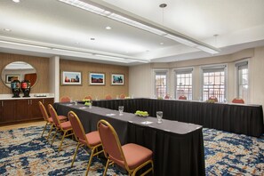 Un salón de conferencias con una mesa larga, sillas y cuadros en la pared.