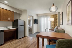 Habitación de hotel compacta con kitchenette, comedor, televisor y cama.