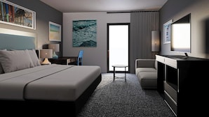 A hotel room with a bed, a desk, a chair, a TV, and artwork on the walls.