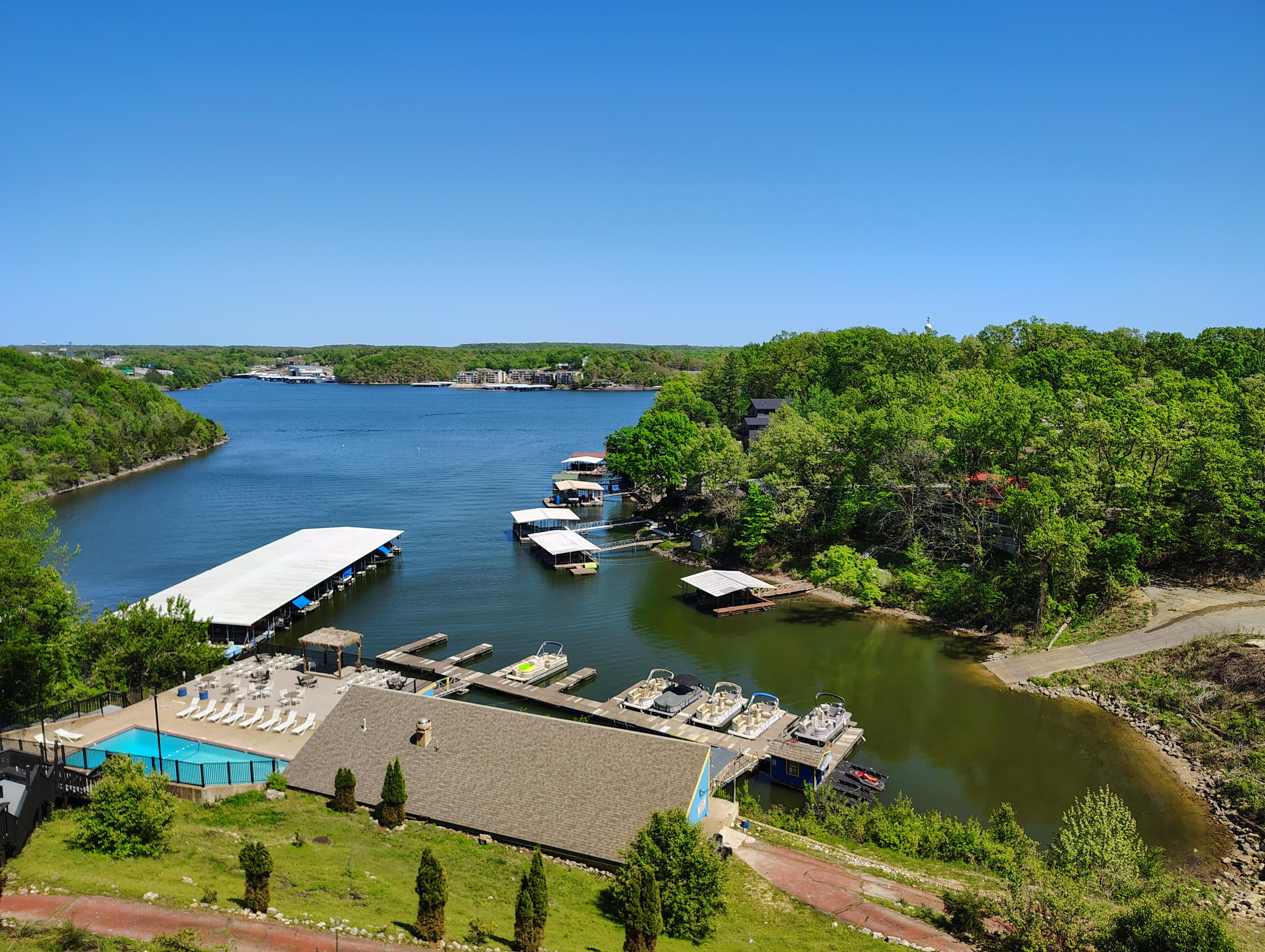 A riverside dock with boats, a swimming pool, and a building with a flat roof.