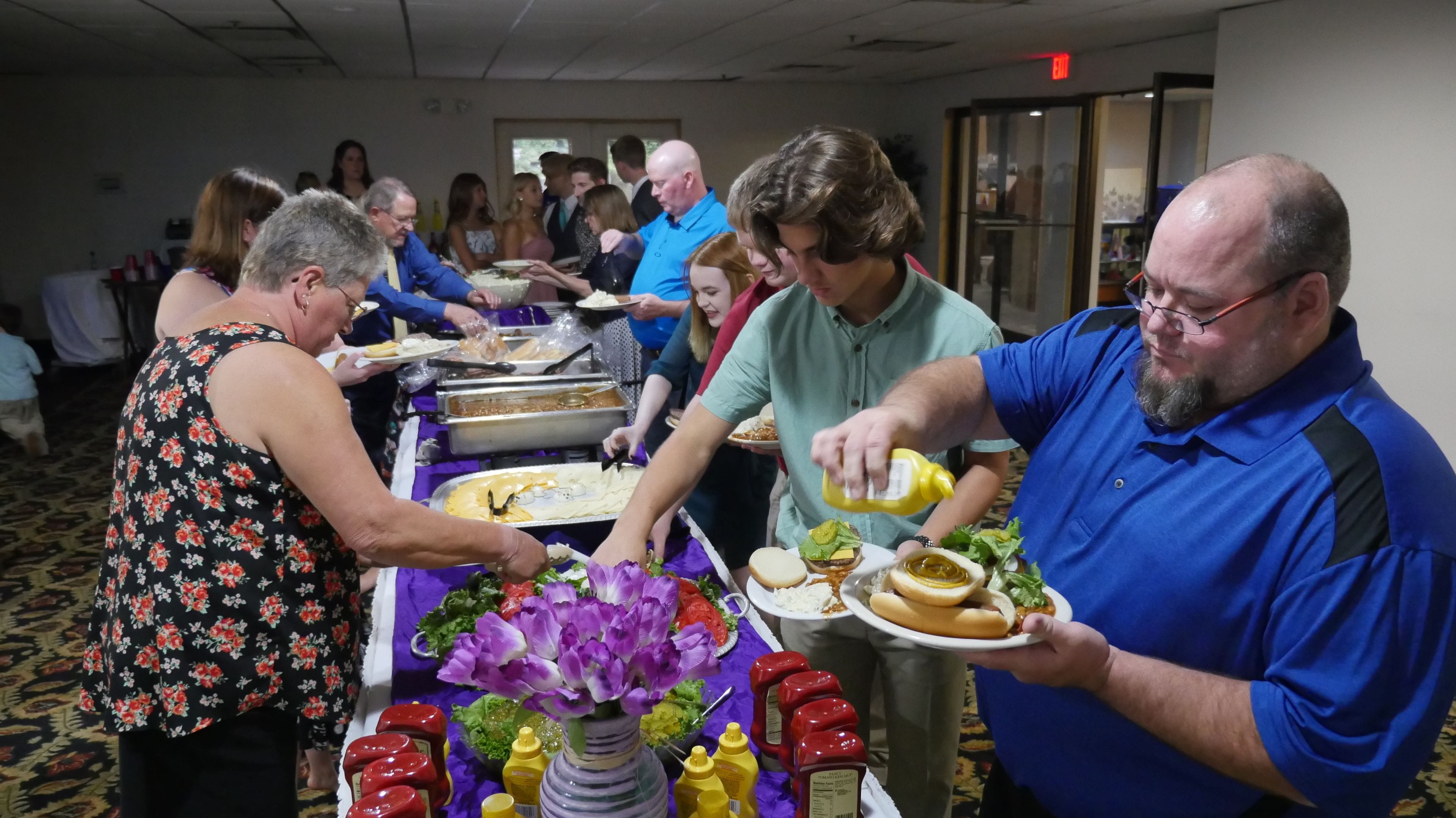 A buffet setup with multiple food stations and attendees serving themselves.