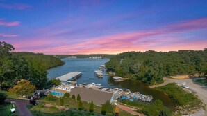 A marina with boats docked, surrounded by greenery and a clear sky.