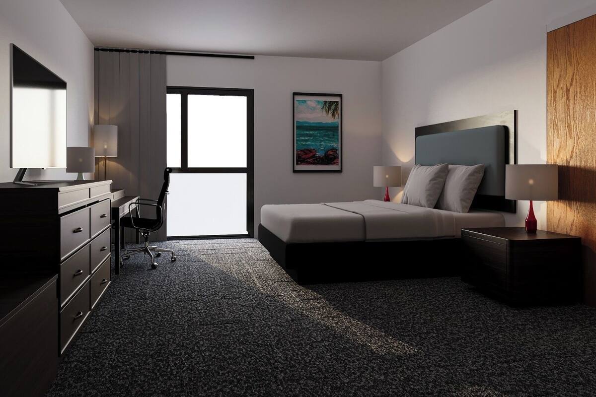 A modern hotel room with a bed, desk, chair, and a large window.
