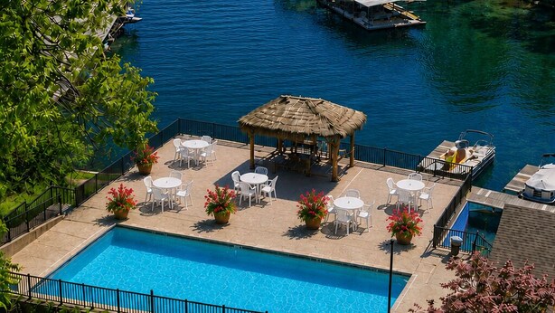 A swimming pool with lounge chairs and a gazebo, surrounded by a dock with boats.