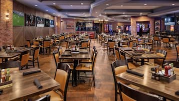 Um restaurante amplo com várias mesas e cabines, paredes de tijolo e objetos de coleção esportiva.
