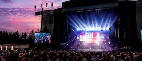 Un gran recinto para conciertos al aire libre con escenario y público.