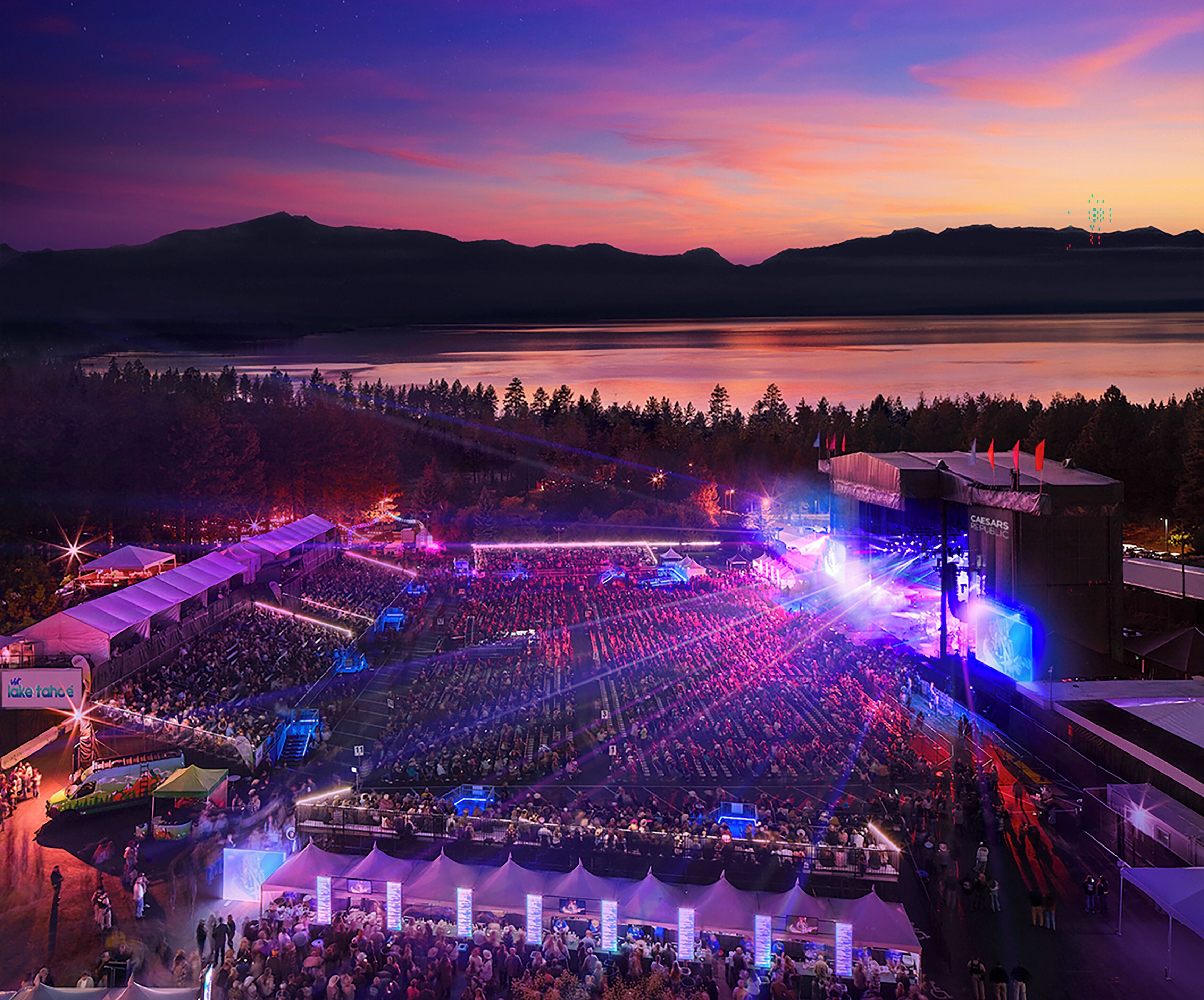 A large outdoor amphitheater with tiered seating, a stage, and a view of a lake and mountains in the background.