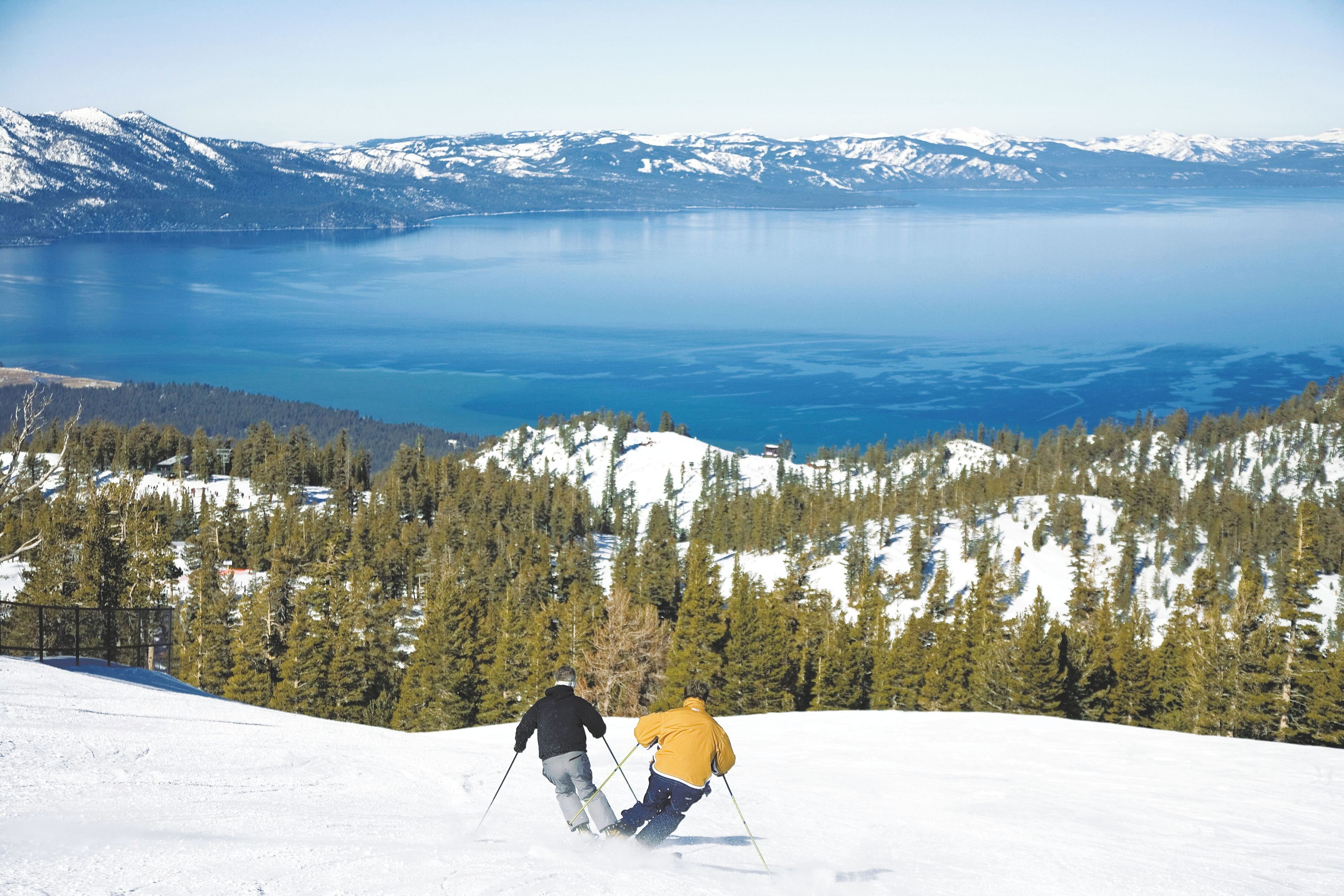 A snowy mountain landscape with a lake and forested area.