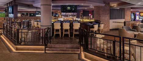 Un amplio bar con diversas opciones de asientos, una pantalla de televisión y una variedad de equipos de bar.