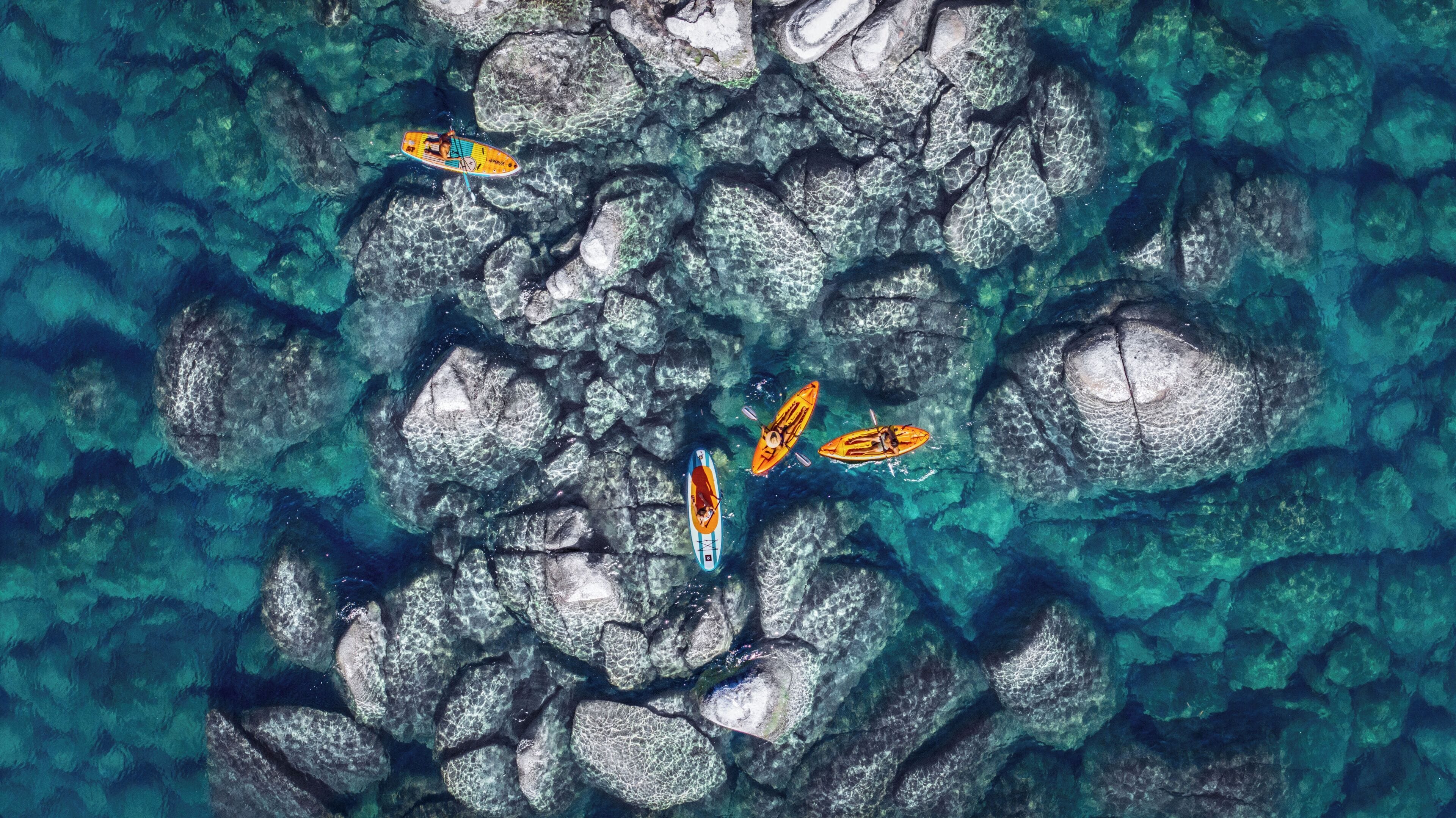 Kayaks on a rocky surface with clear water.