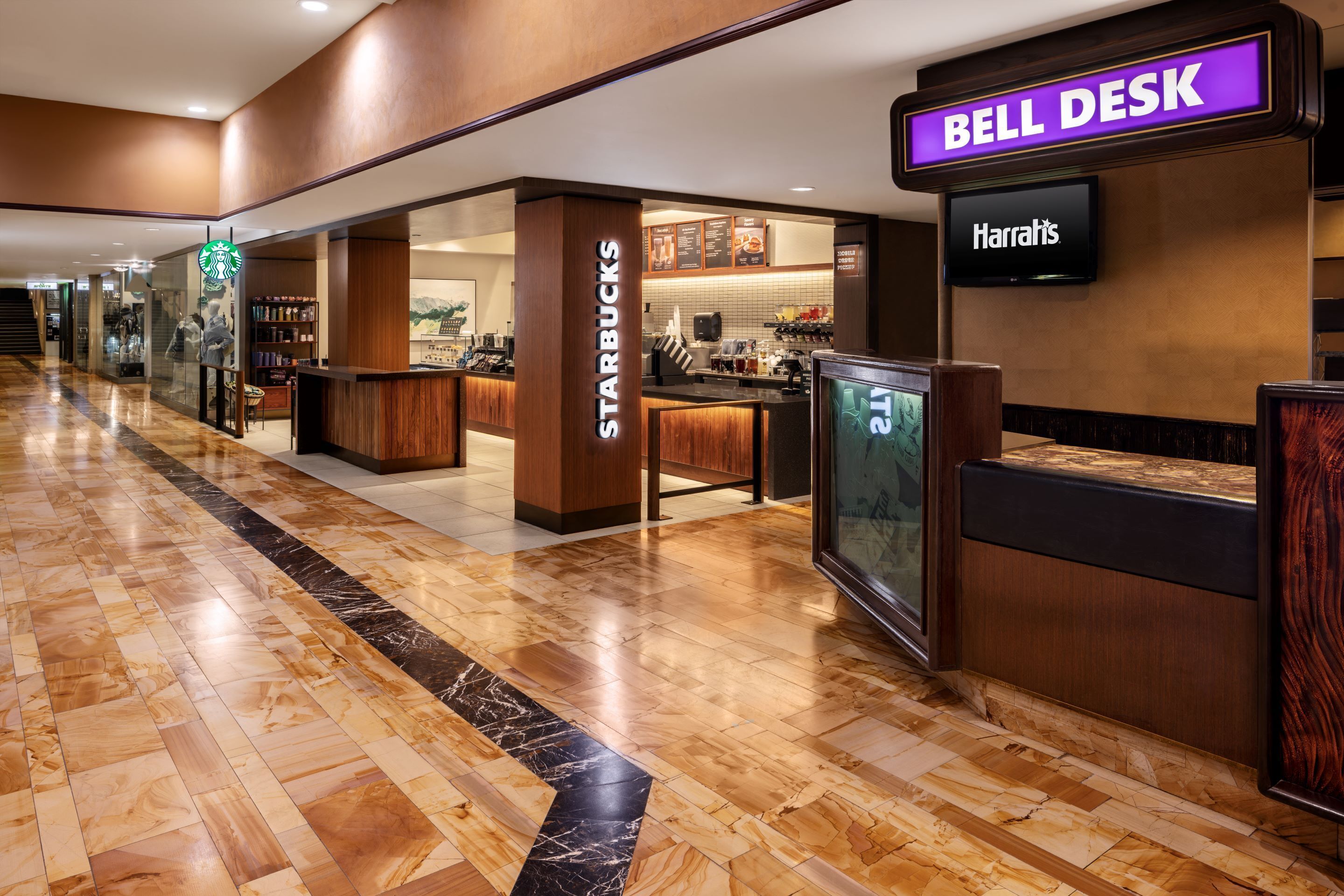 A hotel lobby with a Starbucks and Harrahs, a Bell Desk, and a polished marble floor.