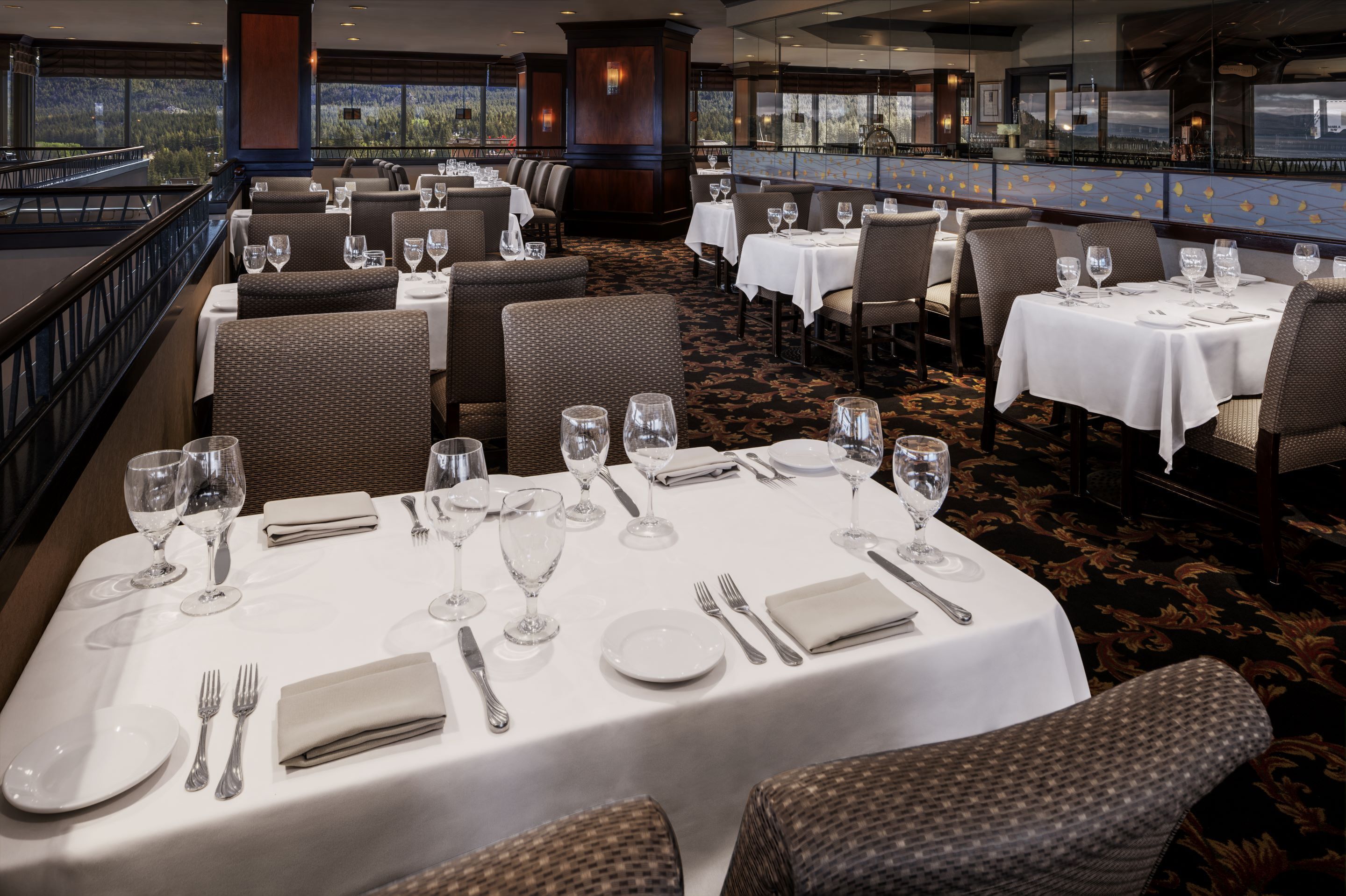 A restaurant with tables set for dining, featuring a view of the outdoors.
