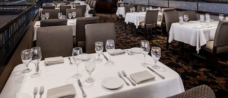 A restaurant with tables set for dining, featuring a view of the outdoors.