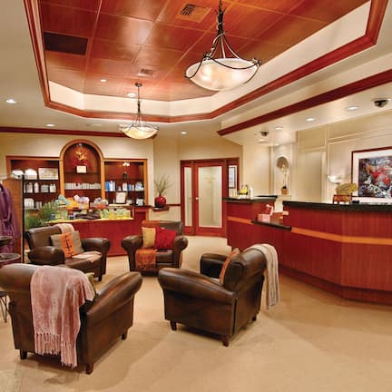A lobby with leather sofas, a reception desk, and a display of items on shelves.
