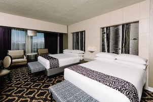 A hotel room with two beds, a sofa, a chair, and a patterned carpet.