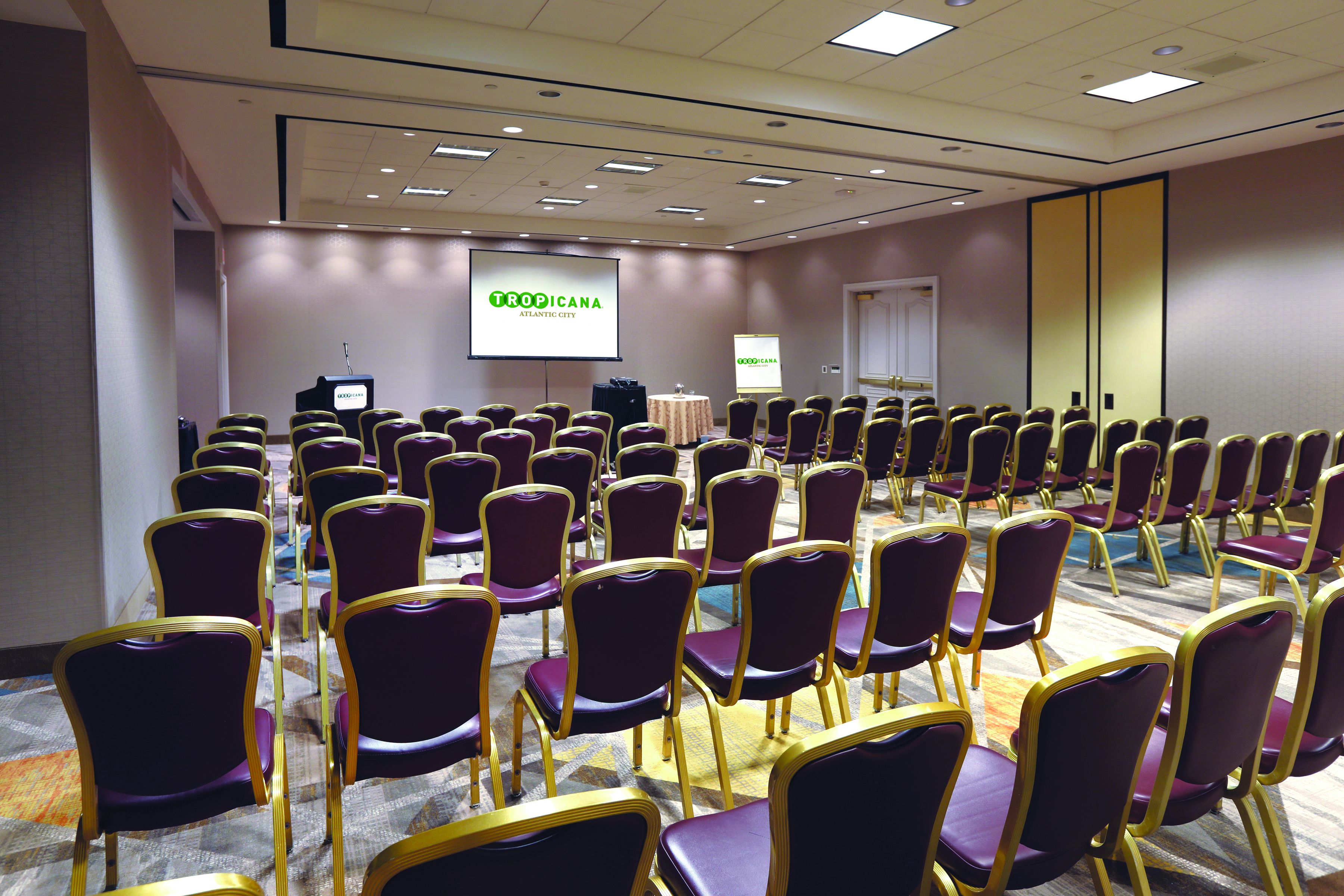 A conference room with rows of purple chairs and a presentation screen.