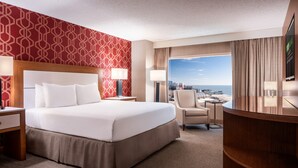 Ein Hotelzimmer mit einem großen Bett, einem Schreibtisch, einem Stuhl und Blick auf die Stadt.