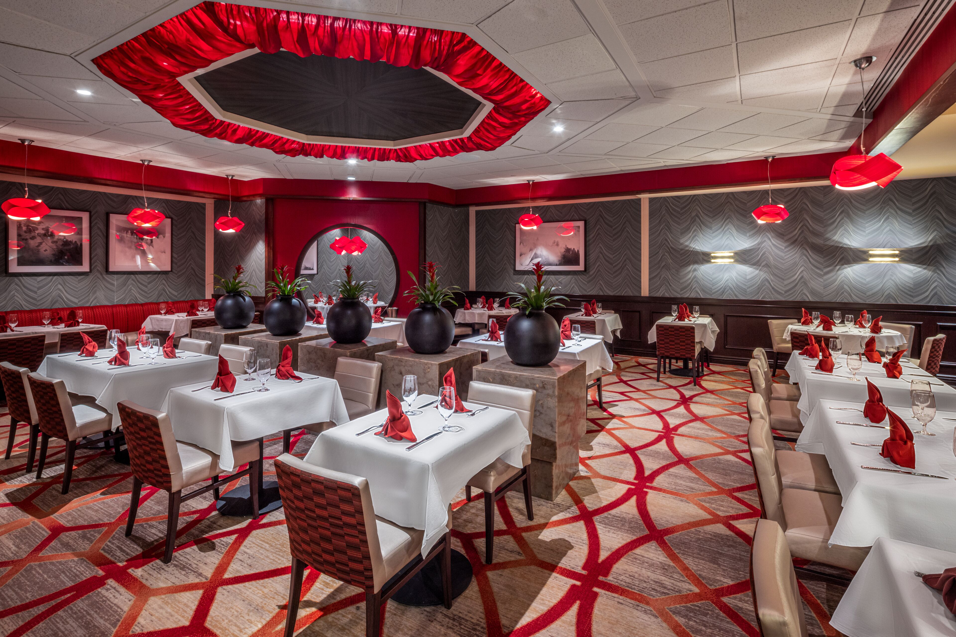 Comedor de hotel con varias mesas, detalles en rojo y decoración moderna.