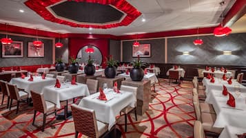 A hotel dining area with multiple tables, red accents, and modern decor.